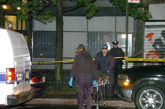 Medical Examiner's Office workers carry away the body of a woman who died early on Tuesday morning in Harlem.